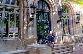 photo of a student walking into a residence hall