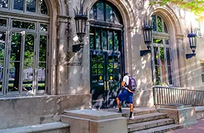 photo of a student walking into a residence hall